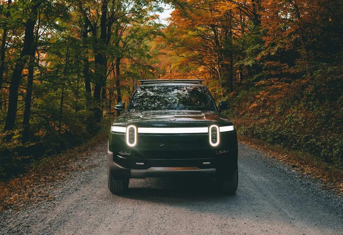 Rivian car driving on a tree-lined road